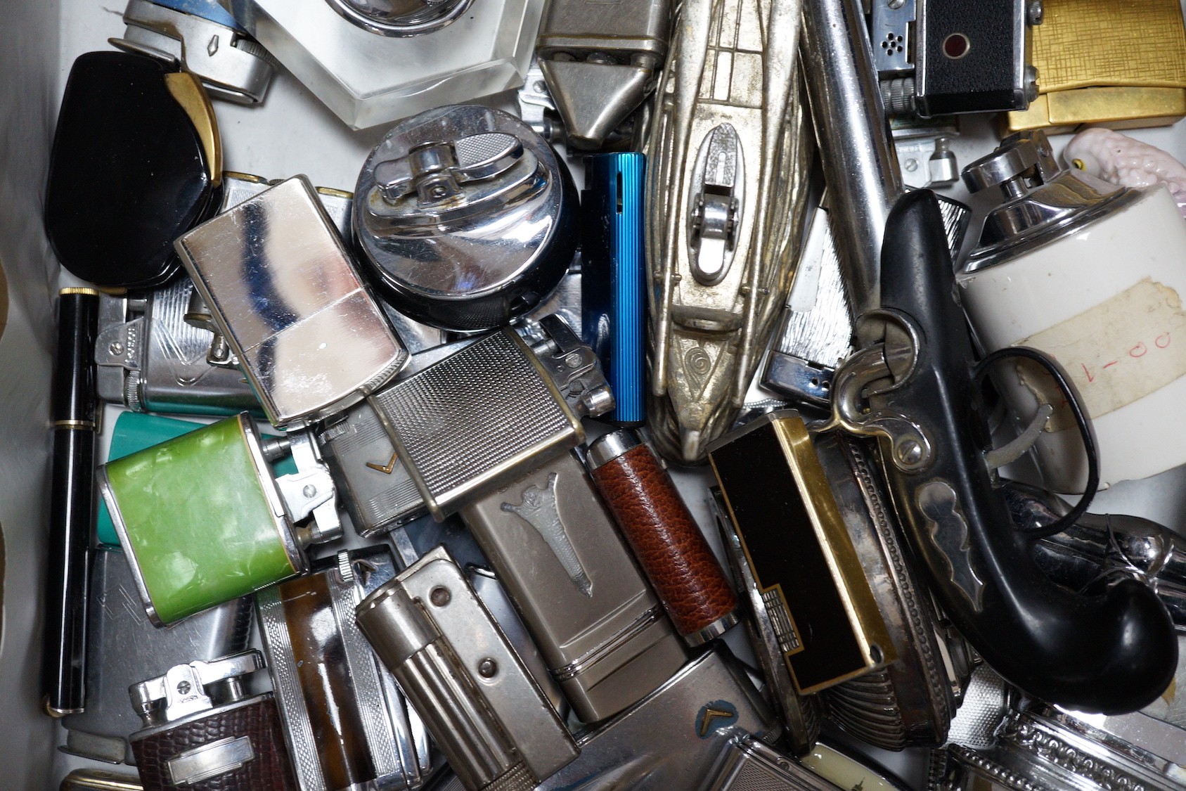 A collection of lighters including some novelty examples such as a percussion cup pistol, a KKW lighter camera, and a spy camera lighter